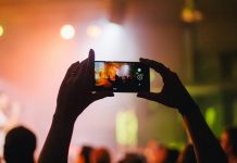 person holding smartphone while taking videos at live concert