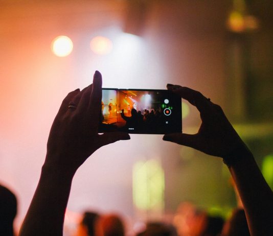 person holding smartphone while taking videos at live concert